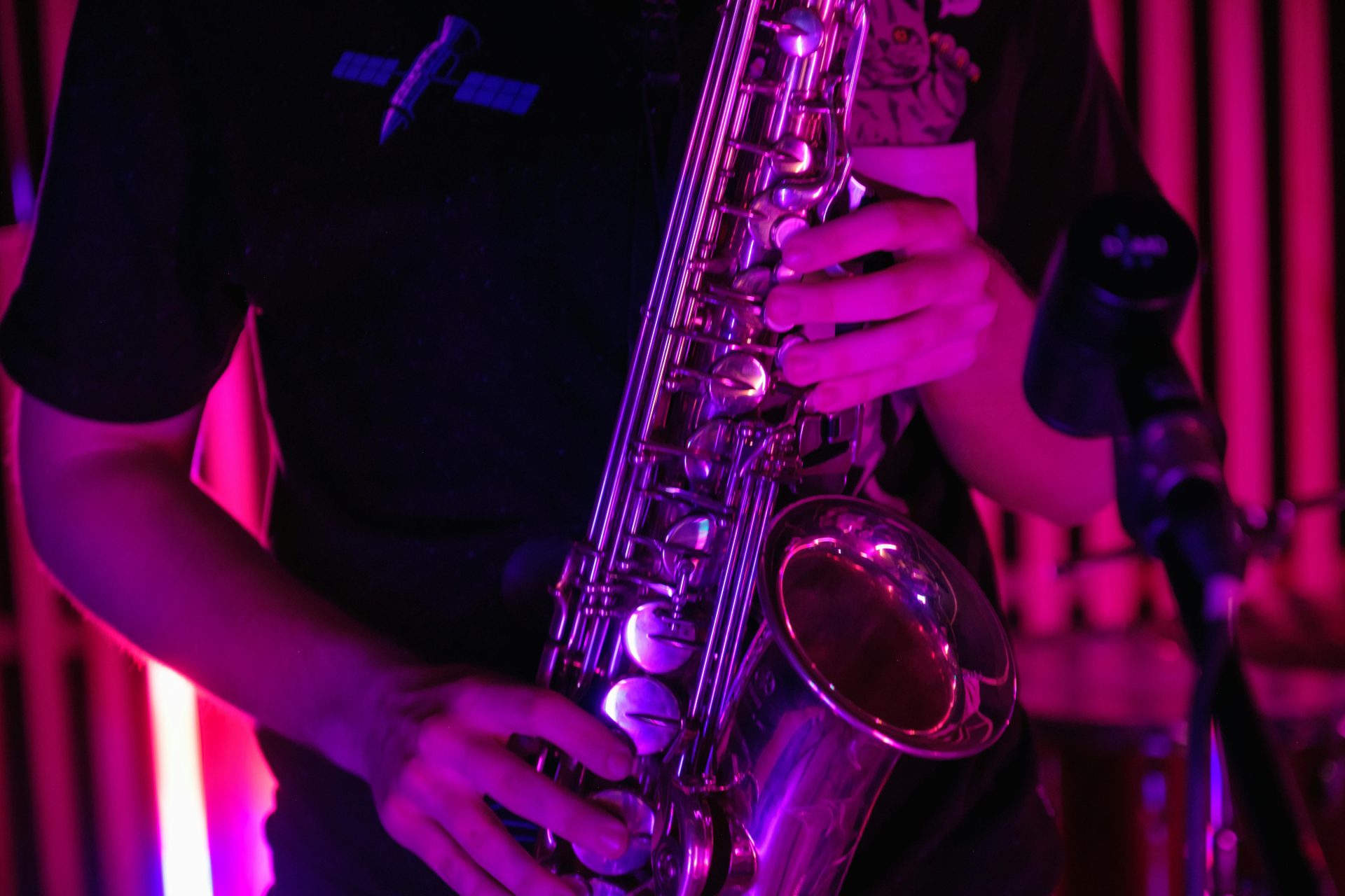 A musician plays a saxophone under vibrant purple lighting, creating a dynamic and engaging atmosphere.